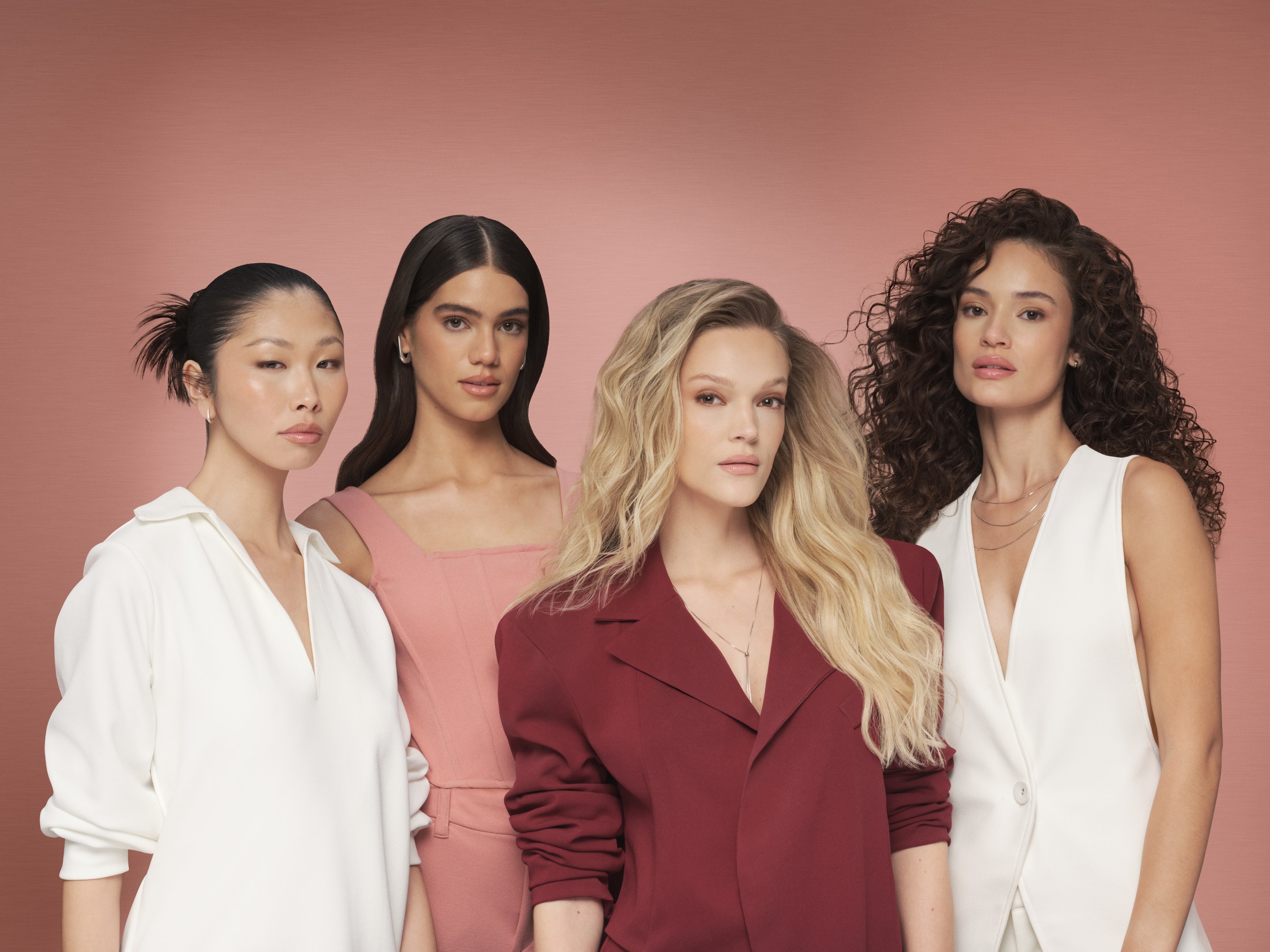 Four models in white, pink and burgundy stand together against a dusty pink backdrop for Nexxus