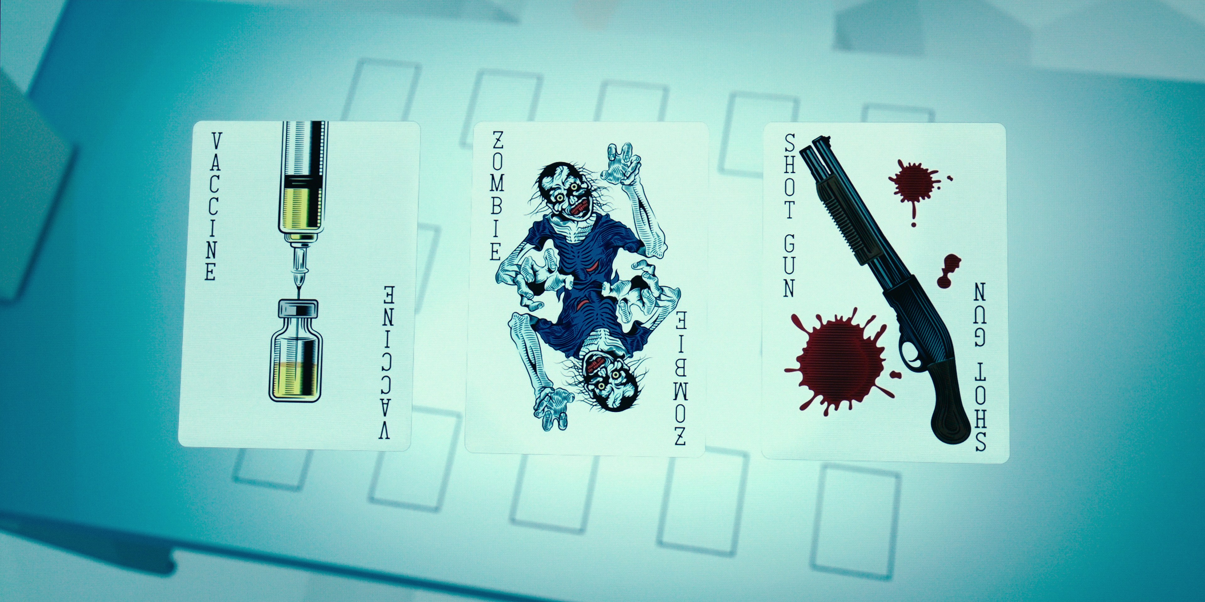 Three illustrated playing cards labeled "Vaccine", "Zombie" and "Shot Gun" laid out on a pale blue game board