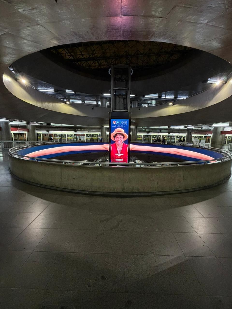 Digital One Piece ad on a metro station column, a straw-hatted character's stretched arms circling the atrium