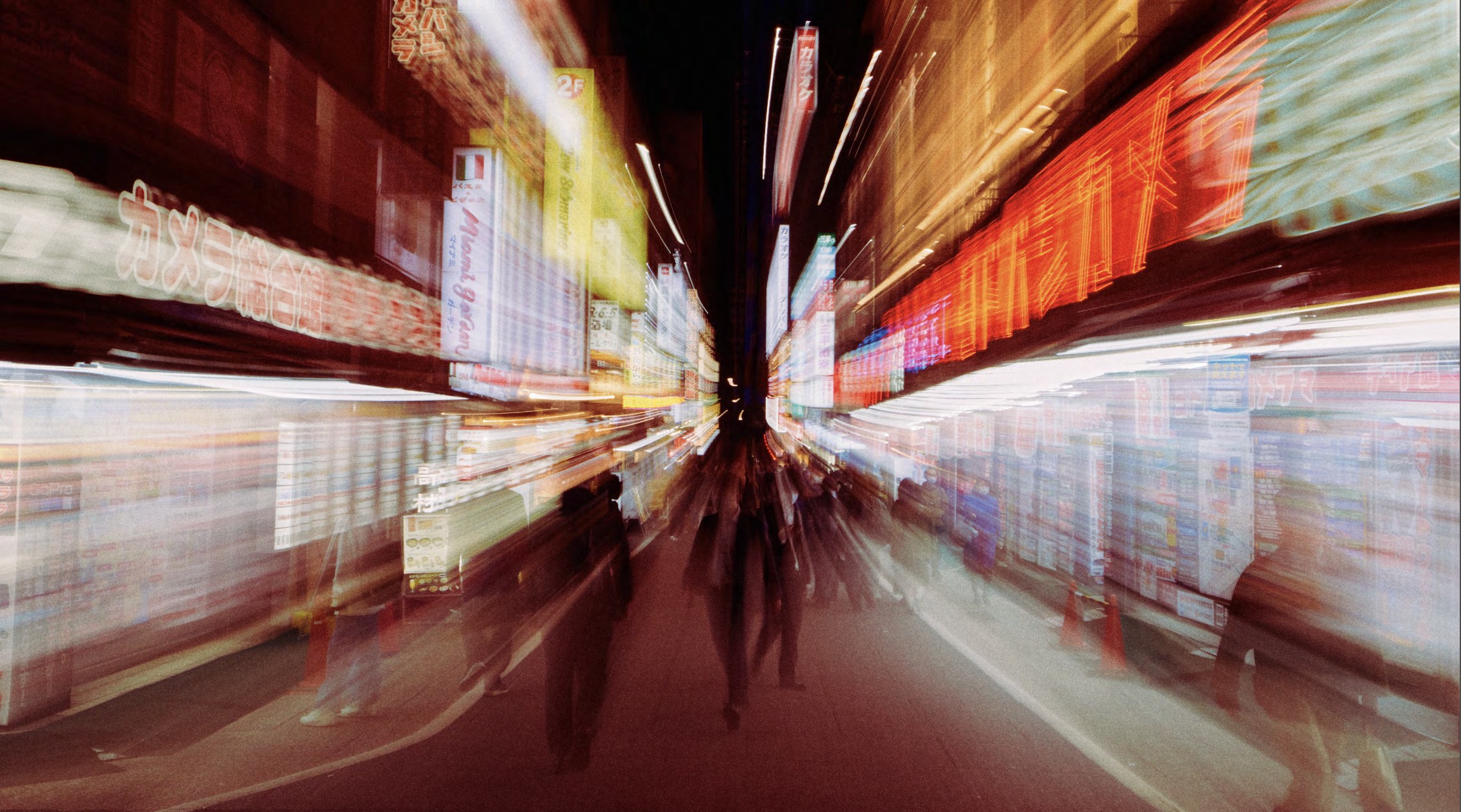 Long-exposure blur of a neon-lit shopping street at night with pedestrians streaking past